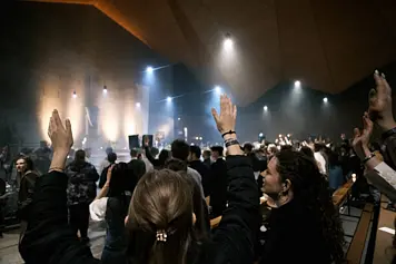 Holy Saturday celebration at Osterforum 2025, wide photograph of a church interior. People raised arms to celebrate the resurrection of Jesus Christ.